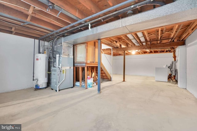 unfinished basement with gas water heater, heating unit, and washer / dryer