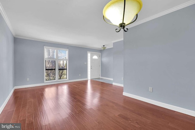 spare room with crown molding, wood finished floors, and baseboards