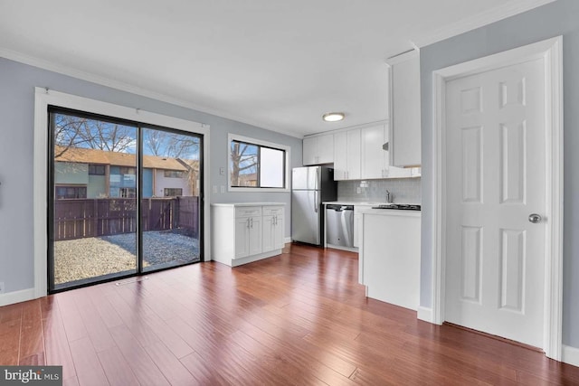 kitchen featuring tasteful backsplash, light countertops, stainless steel appliances, wood finished floors, and white cabinetry