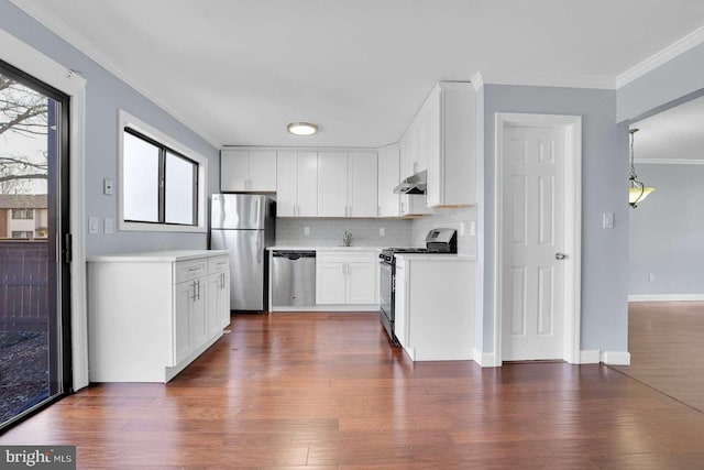 kitchen featuring under cabinet range hood, dark wood-type flooring, appliances with stainless steel finishes, and ornamental molding