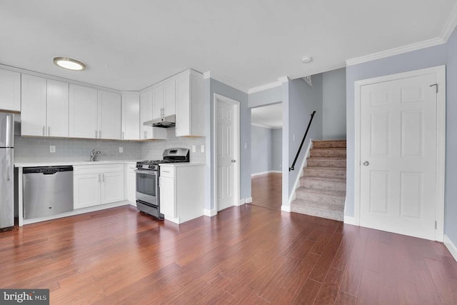 kitchen with stainless steel appliances, light countertops, white cabinets, under cabinet range hood, and tasteful backsplash