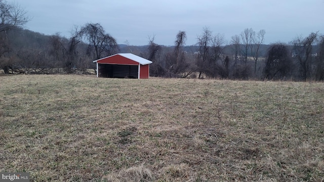 view of yard featuring a rural view, a pole building, and an outdoor structure