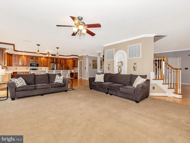 living area featuring crown molding, ceiling fan, light colored carpet, and visible vents
