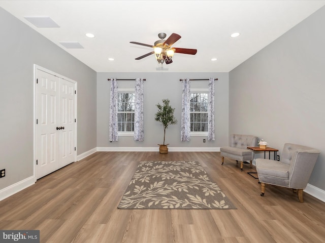 living area featuring a healthy amount of sunlight, baseboards, a ceiling fan, and wood finished floors