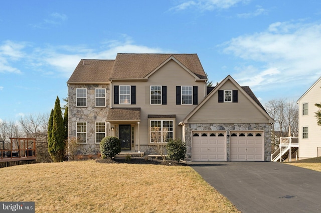 view of front facade with aphalt driveway, stone siding, a front lawn, and a garage