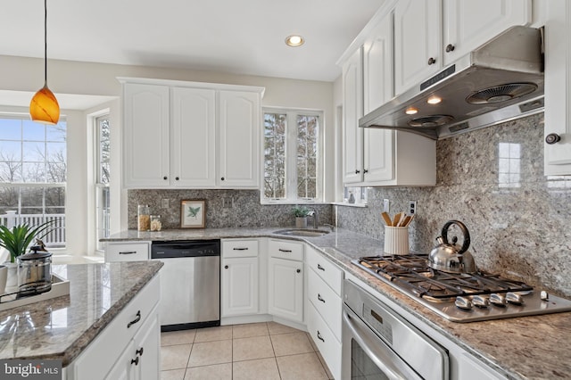 kitchen with under cabinet range hood, a sink, tasteful backsplash, appliances with stainless steel finishes, and white cabinets