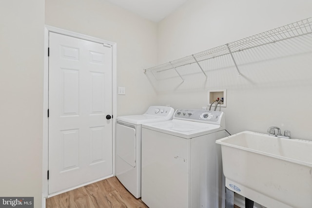 laundry room with washer and dryer, laundry area, light wood-style flooring, and a sink