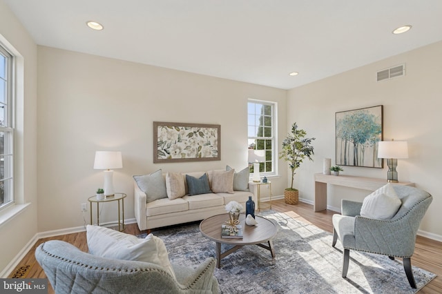 living area with wood finished floors, visible vents, and baseboards