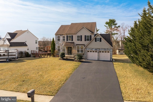 view of front facade with a front lawn, aphalt driveway, a deck, stone siding, and an attached garage