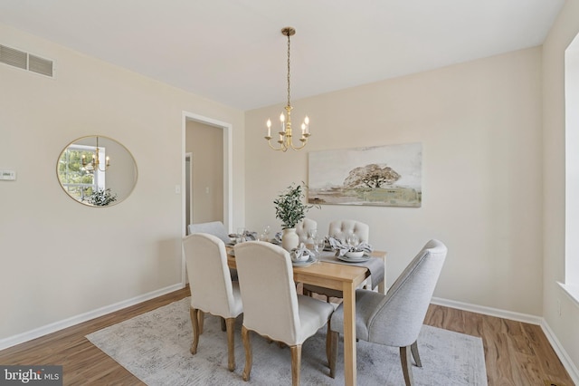 dining area with visible vents, baseboards, an inviting chandelier, and wood finished floors