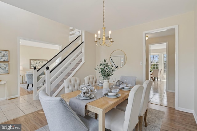 dining space featuring stairs, a notable chandelier, light wood-style floors, and baseboards