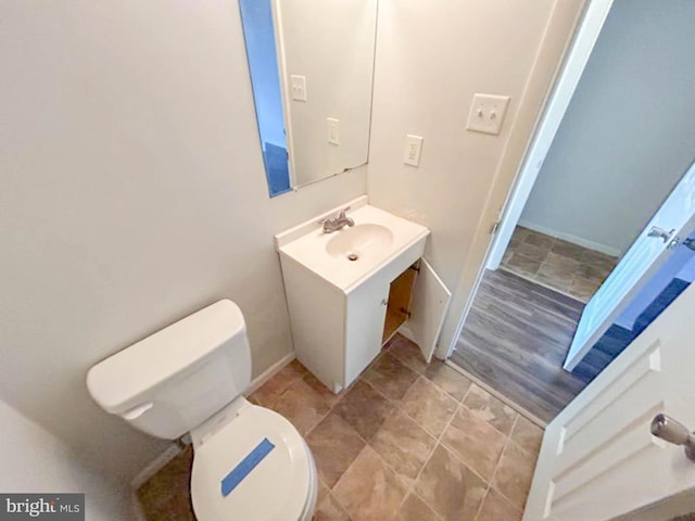 half bath with toilet, vanity, and baseboards