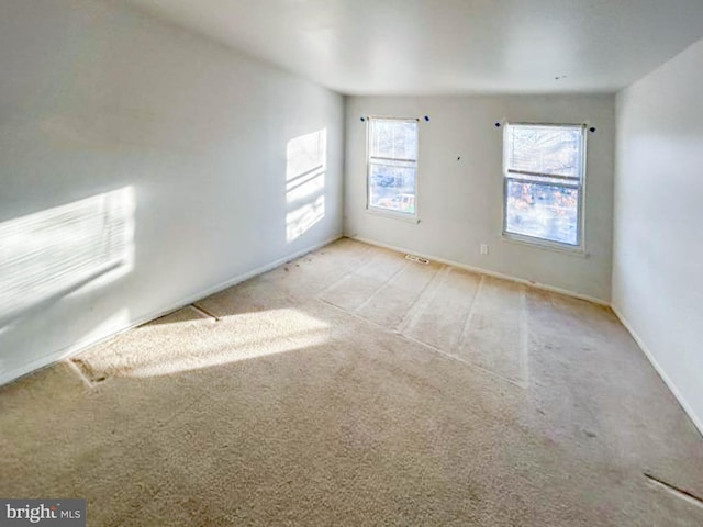 unfurnished room featuring baseboards and light carpet