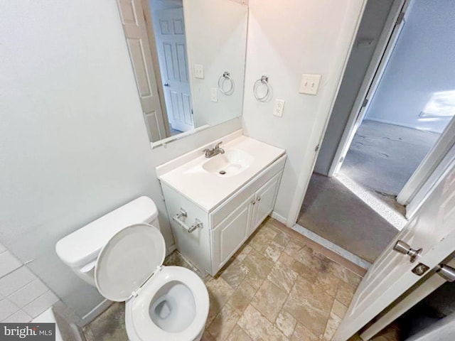 half bathroom with toilet, vanity, and stone finish floor