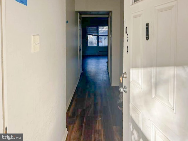 corridor with dark wood-type flooring and baseboards