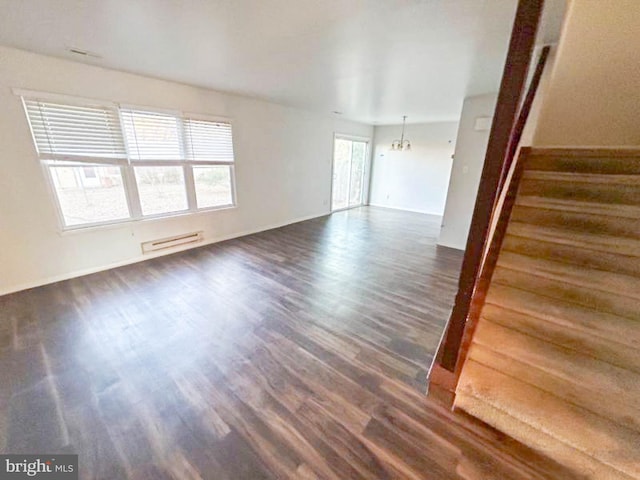 unfurnished living room with stairway, baseboards, dark wood-type flooring, baseboard heating, and a chandelier