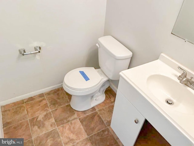 bathroom with baseboards, toilet, and vanity