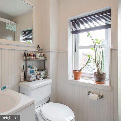 bathroom featuring a sink, toilet, and wainscoting