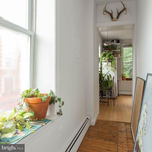 corridor featuring hardwood / wood-style floors and a baseboard heating unit