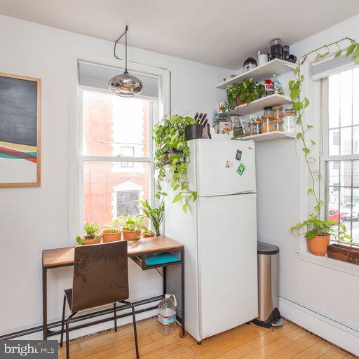 kitchen featuring baseboard heating, plenty of natural light, freestanding refrigerator, and light wood-style floors