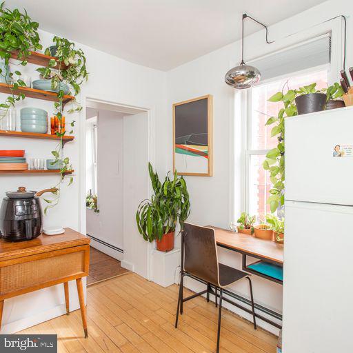 dining area with light wood-type flooring and baseboard heating