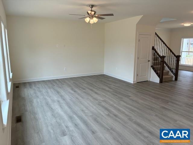 unfurnished living room with visible vents, ceiling fan, baseboards, stairs, and wood finished floors