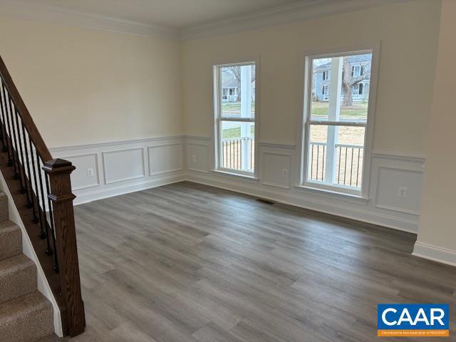 interior space featuring stairway, a healthy amount of sunlight, ornamental molding, and dark wood finished floors