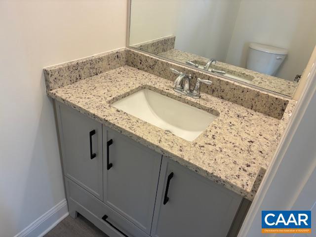 half bath with toilet, vanity, and baseboards