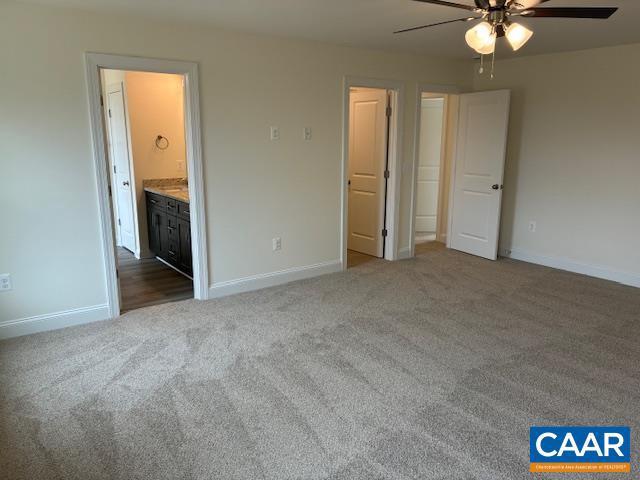 unfurnished bedroom with a ceiling fan, baseboards, carpet, and ensuite bathroom