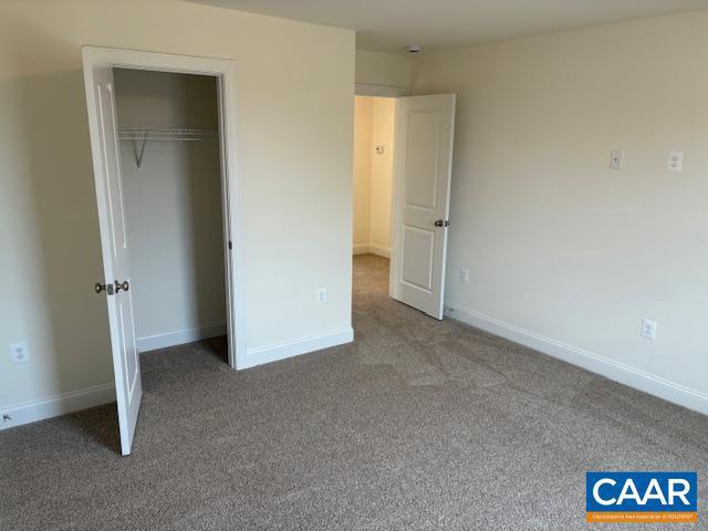 unfurnished bedroom with a closet, baseboards, and carpet