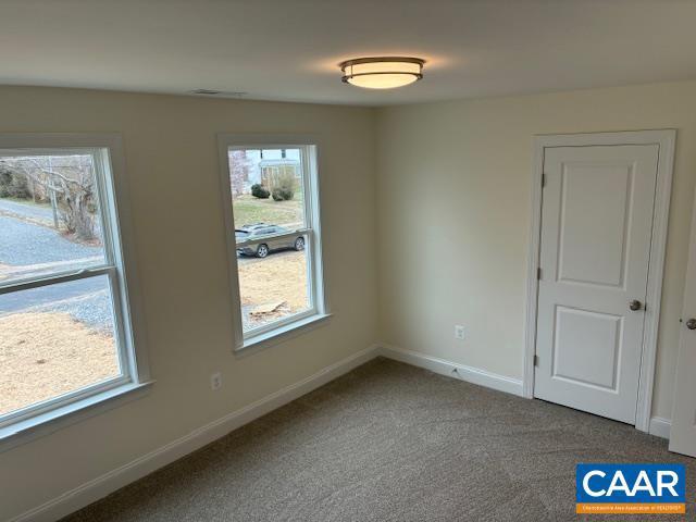 unfurnished room with baseboards, carpet floors, and visible vents