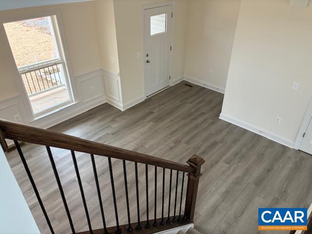 entrance foyer with stairway, a wainscoted wall, wood finished floors, and a decorative wall