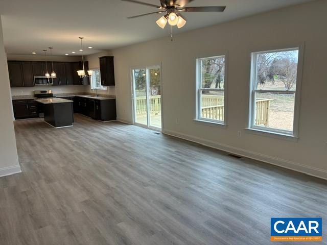 kitchen featuring baseboards, open floor plan, appliances with stainless steel finishes, and a kitchen island