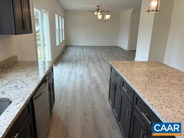 kitchen with light stone counters, light wood-type flooring, and stainless steel dishwasher