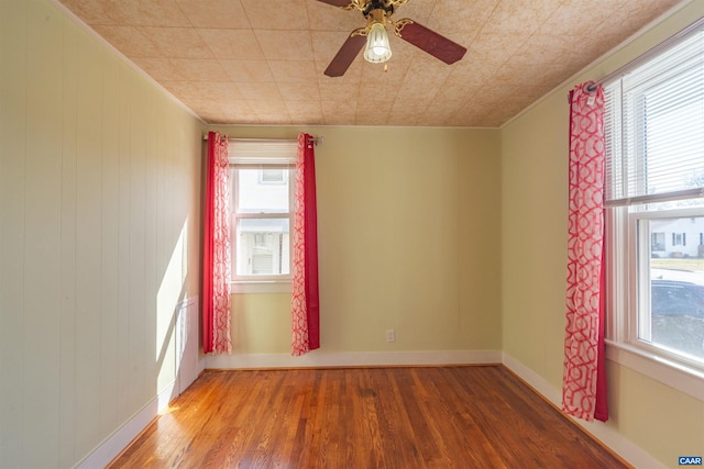 empty room featuring ceiling fan, baseboards, and wood finished floors