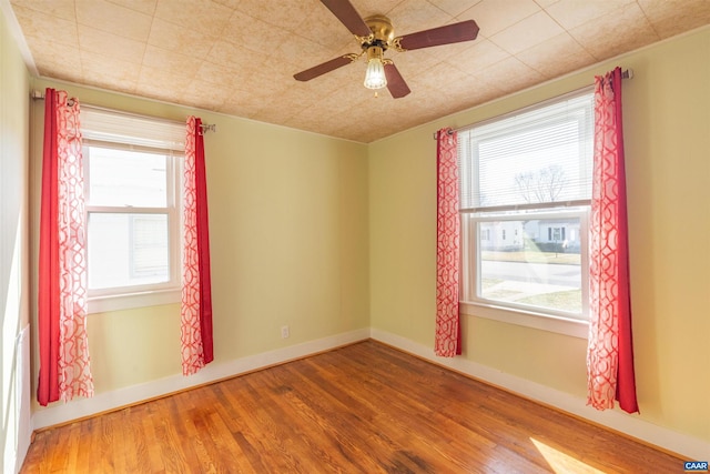 empty room featuring baseboards, wood finished floors, and a ceiling fan