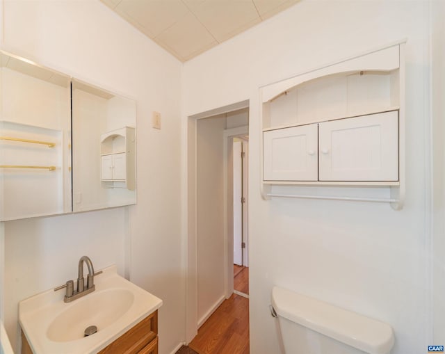 half bath featuring toilet, wood finished floors, and vanity