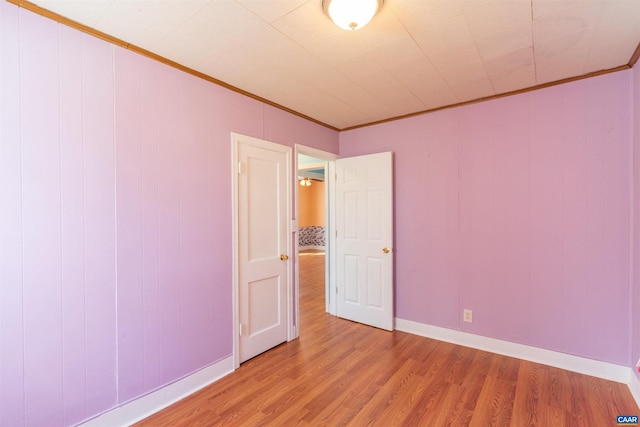 empty room with baseboards, light wood-style flooring, and ornamental molding