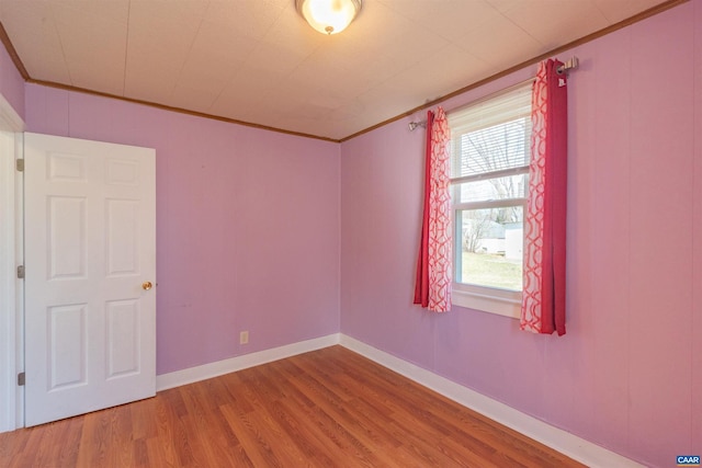 empty room with crown molding, baseboards, and wood finished floors