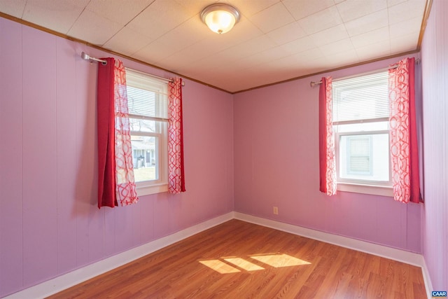 unfurnished room with wood finished floors, baseboards, and ornamental molding