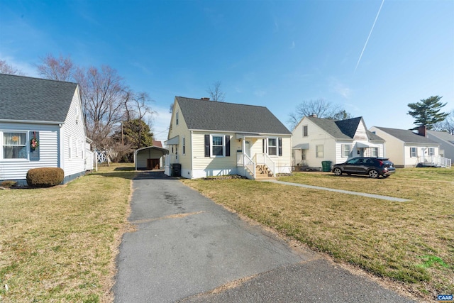 view of front of house with a detached carport, a residential view, driveway, and a front lawn