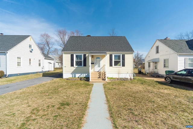 bungalow-style home featuring roof with shingles, a front lawn, and entry steps