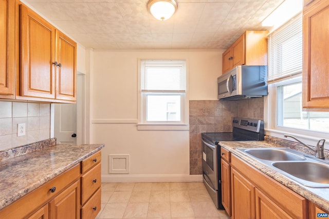 kitchen featuring a sink, plenty of natural light, brown cabinets, and stainless steel appliances