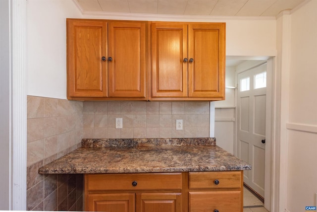 kitchen with decorative backsplash, crown molding, and brown cabinetry