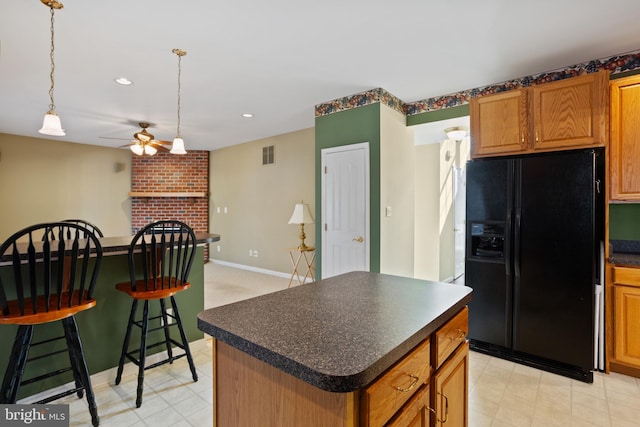 kitchen with visible vents, black fridge with ice dispenser, dark countertops, a center island, and ceiling fan