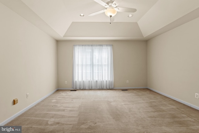 spare room with baseboards, a raised ceiling, and a ceiling fan