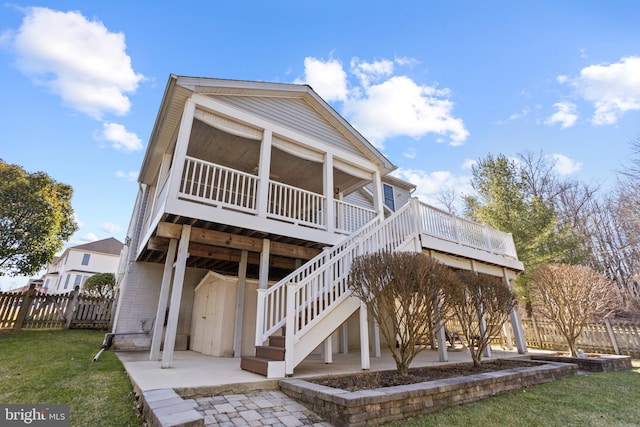 rear view of house with a patio, a lawn, stairs, and fence