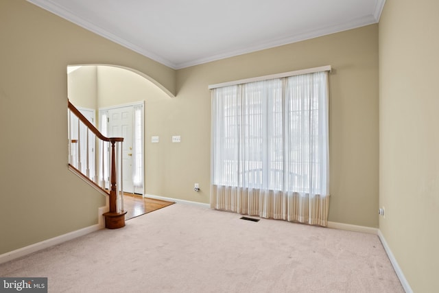 entrance foyer with visible vents, baseboards, ornamental molding, and carpet flooring