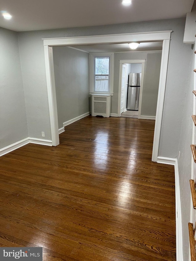 spare room featuring radiator heating unit, baseboards, and wood finished floors