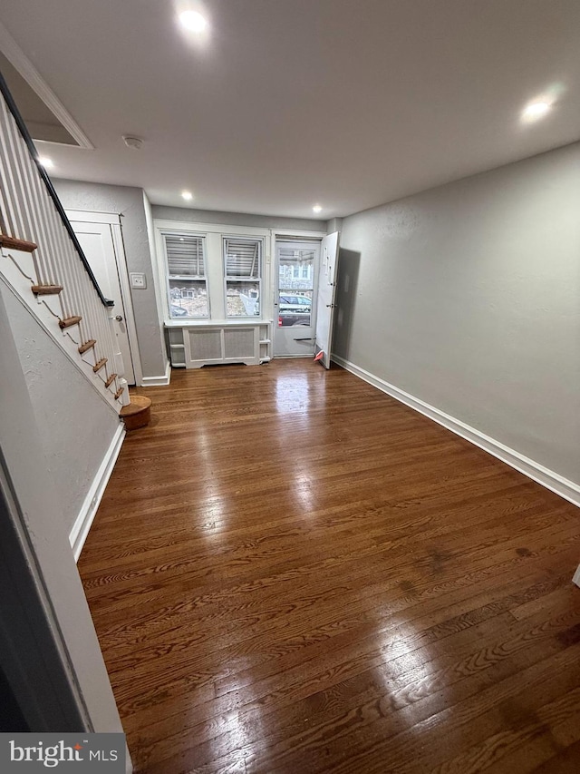 unfurnished living room featuring baseboards, wood finished floors, and stairs